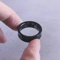 Black titanium smart ring held between two fingers