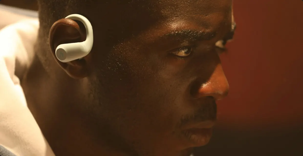 Man wearing an open-ear headphone in warm light