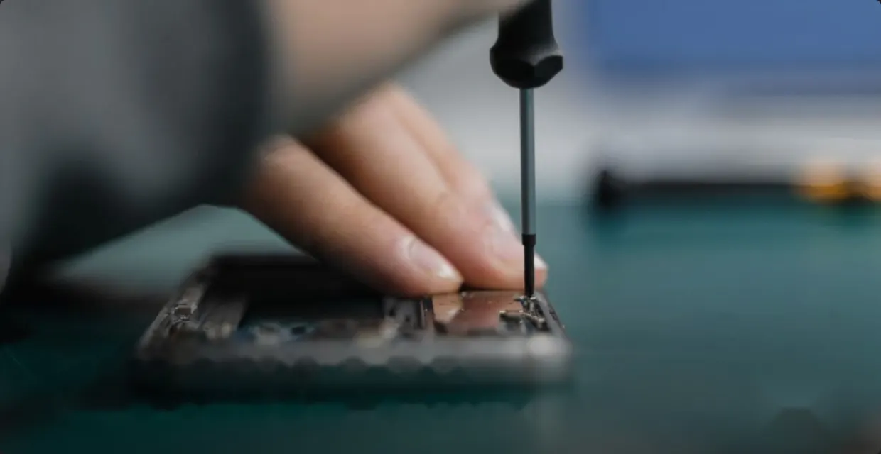 Hands repairing a smartphone with a screwdriver