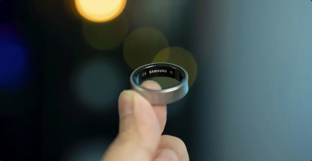 Hand holding a smart ring against blurred lights