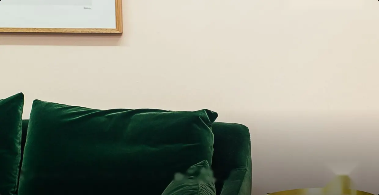 Dark green velvet sofa against a cream wall
