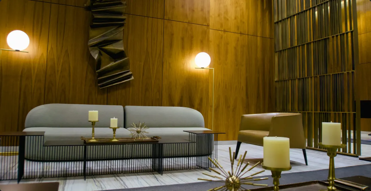 Living room with wood paneling, brass lamps and a gray sofa