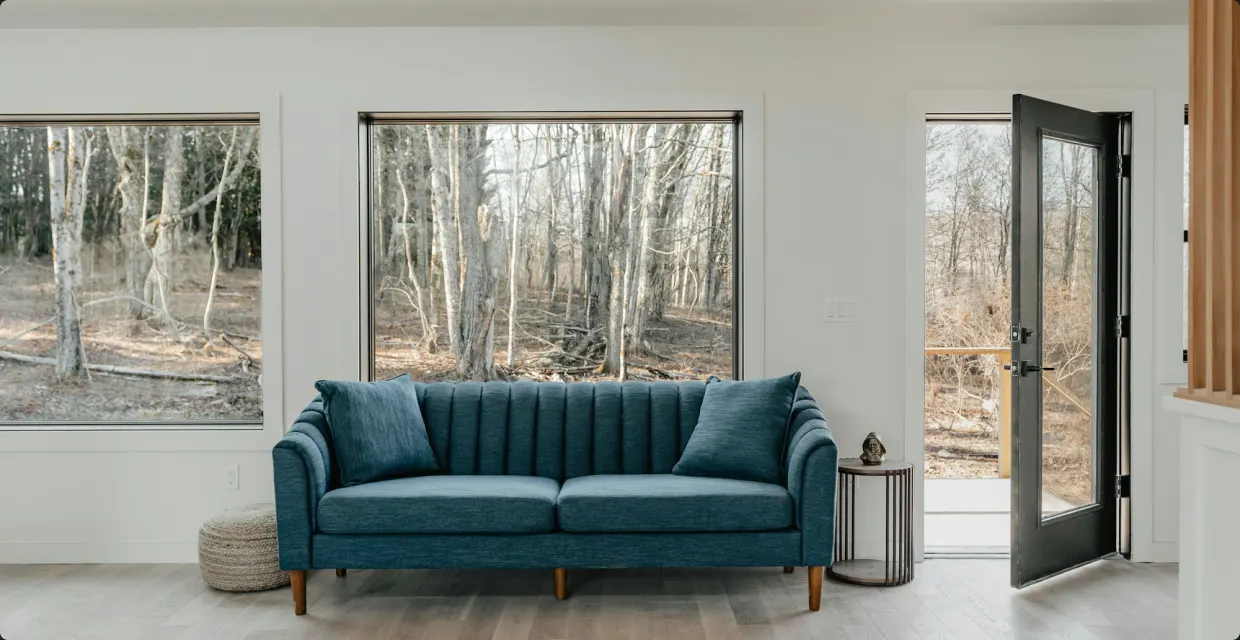 Deep teal sofa in a bright room with large windows
